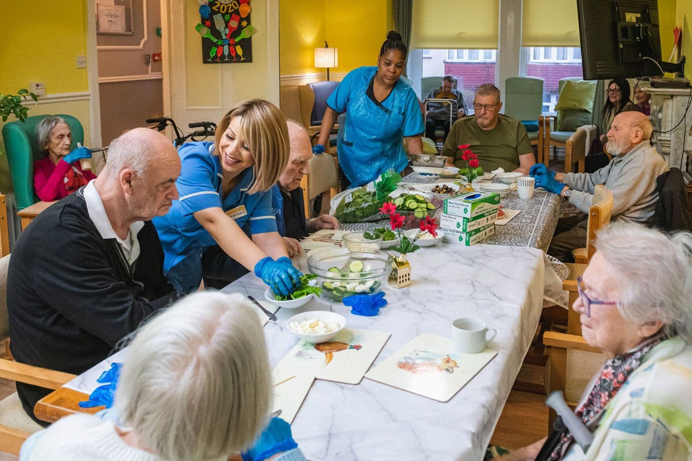 Carers helping residents arrange flowers and leaves at the dining table