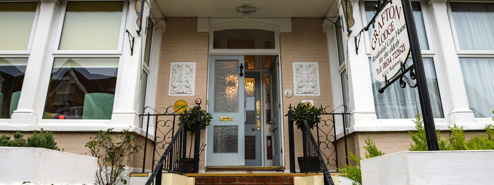 The front door of Grafton Lodge, with steps, railings and potted plants